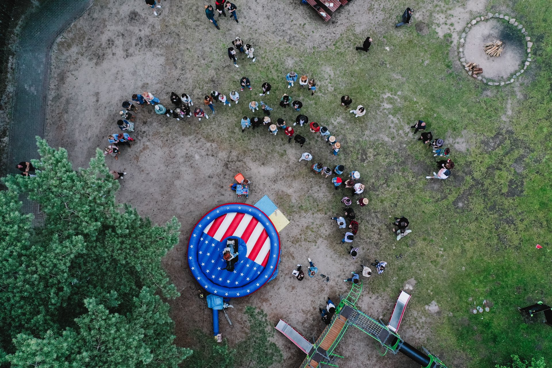 Uczestnicy zgromadzeni wokół strefy atrakcji na pikniku firmowym – ujęcie z drona