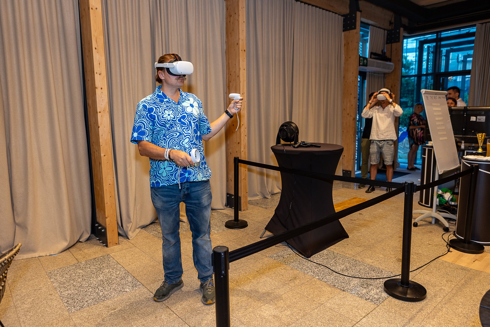 Mężczyzna w goglach VR z kontrolerami – strefa VR na pikniku firmowym