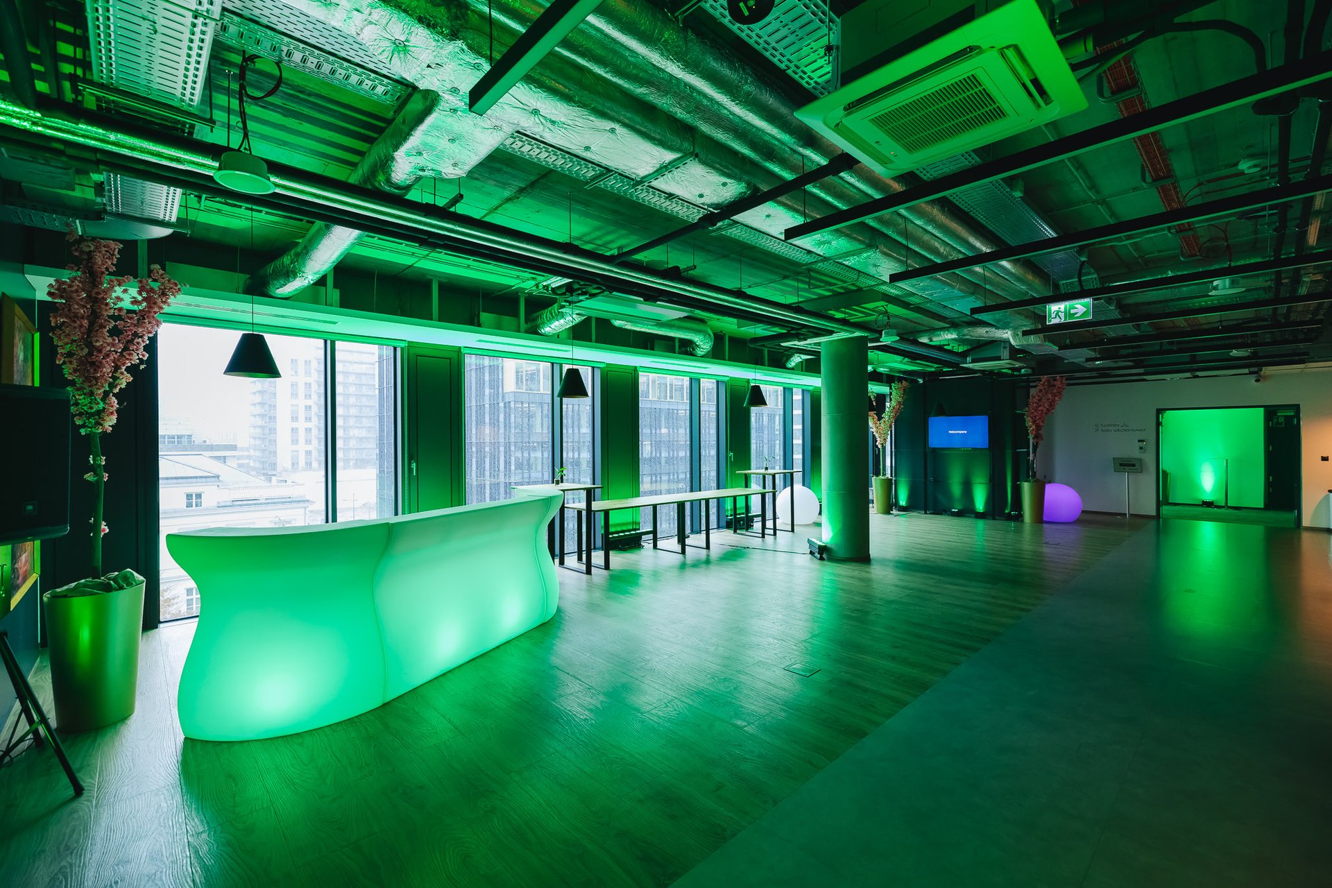 Open space z podświetlanym na zielono barem LED i oknami na panoramę miasta