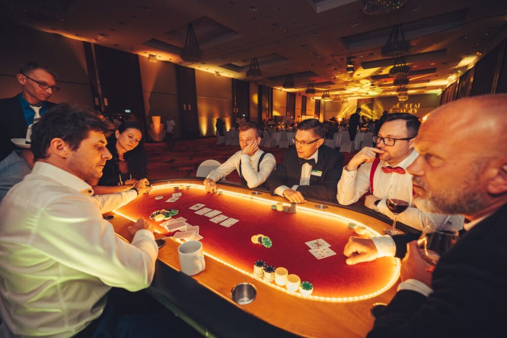 Goście w muszkach i szelkach przy podświetlanym stole pokerowym na Gatsby Party