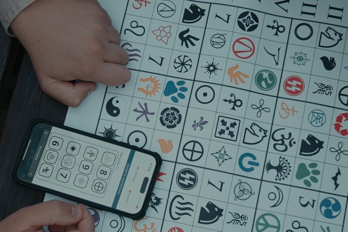 Plansza z symbolami i telefon z klawiaturą szyfru podczas zadania w grze indoorowej
