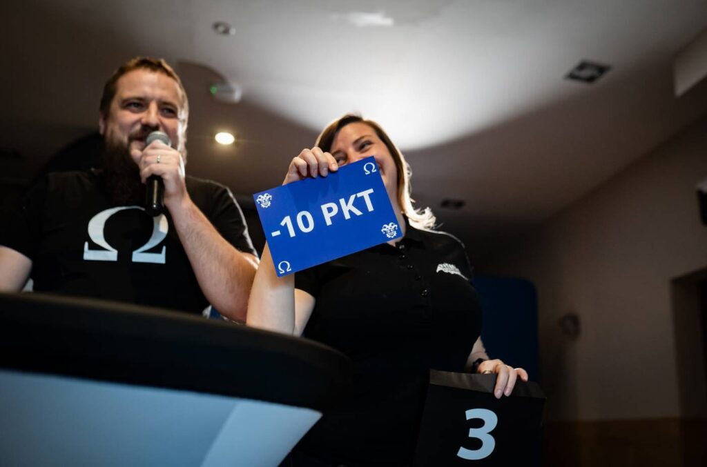 Konferansjer ogłasza punkty karne podczas gry, w tle ranking drużyn