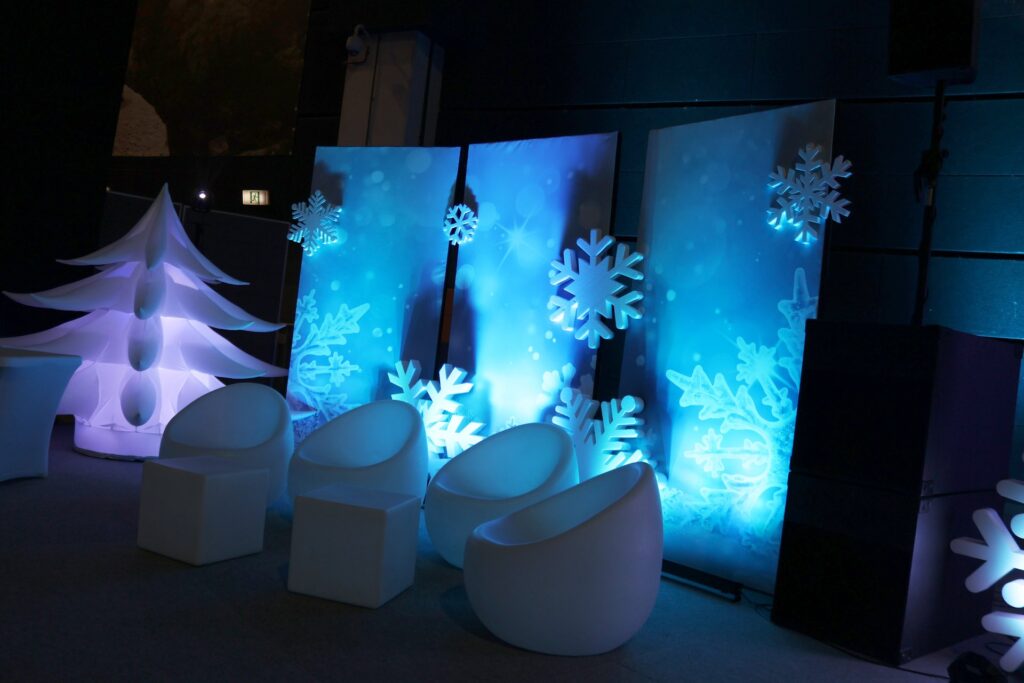 Biała dmuchana choinka i strefa lounge przy podświetlanych panelach ze śnieżynkami - dekoracje Winter Party