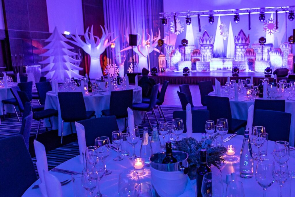 Scena z lodowym zamkiem, białe drzewa, choinki i latarnie przy nakrytych stołach - scenografia Winter Party